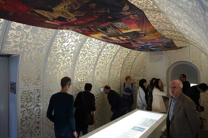 eine Gruppe von Menschen geht durch einen Ausstellungsraum und schaut sich alles interessiert an